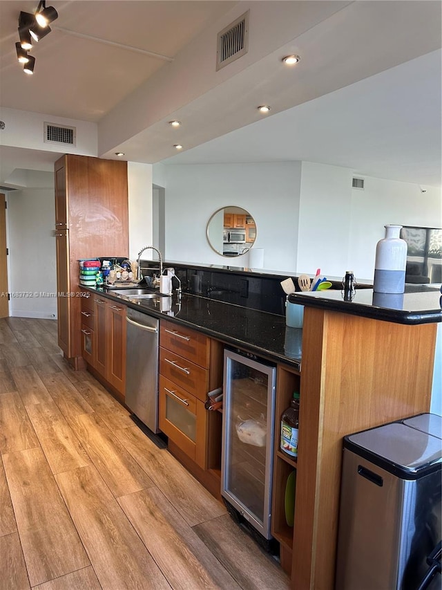 kitchen with dark stone countertops, sink, beverage cooler, dishwasher, and light hardwood / wood-style floors