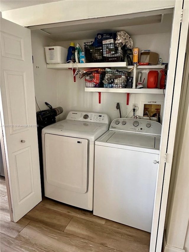 laundry area featuring washing machine and clothes dryer and light hardwood / wood-style flooring