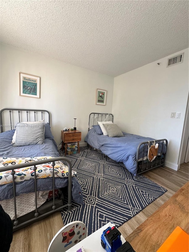 bedroom with a textured ceiling and hardwood / wood-style floors