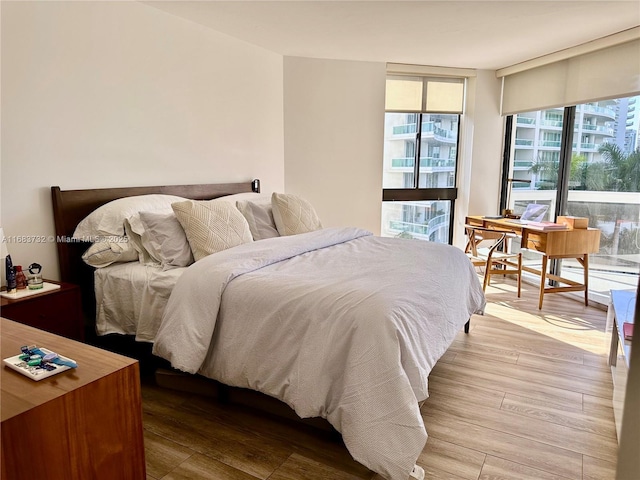 bedroom featuring a wall of windows and light wood-type flooring