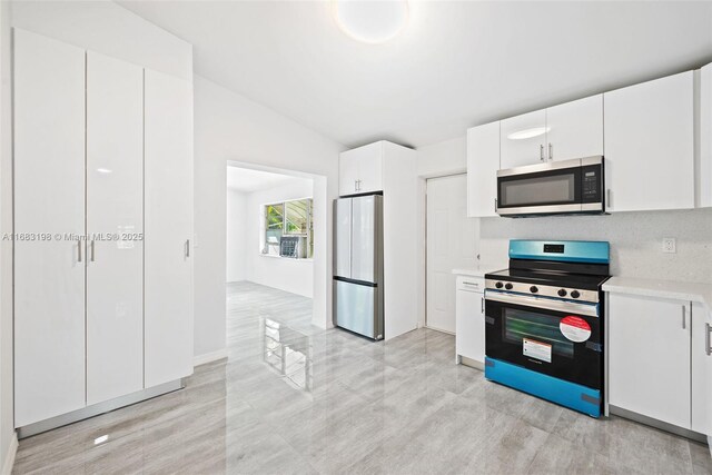 kitchen with white cabinetry, sink, vaulted ceiling, and electric range