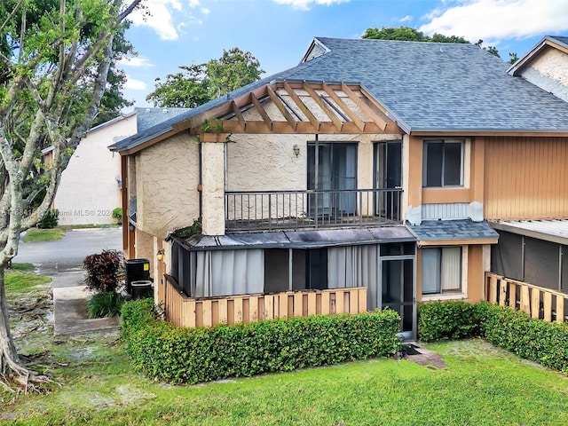 rear view of house featuring central AC unit, a yard, and a balcony