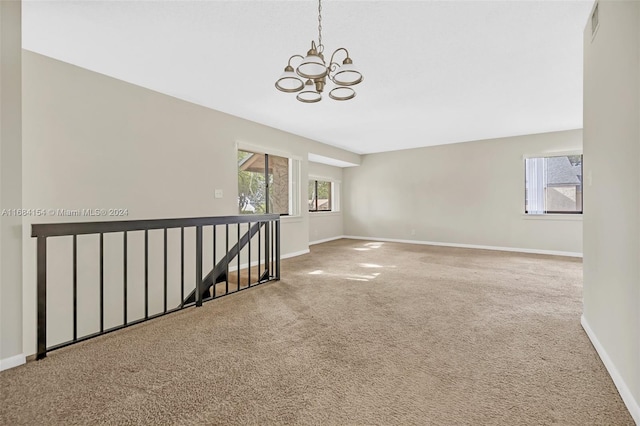 spare room featuring carpet flooring and an inviting chandelier