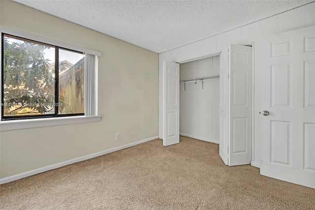 unfurnished bedroom featuring a closet, a textured ceiling, and light carpet