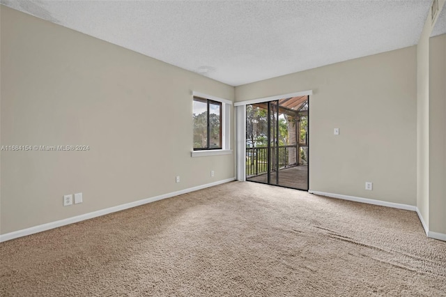 carpeted empty room with a textured ceiling