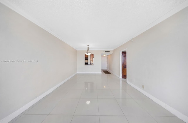 empty room featuring ornamental molding, a textured ceiling, and light tile patterned floors