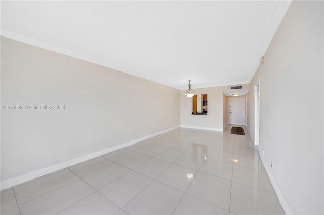 spare room featuring crown molding and light tile patterned flooring