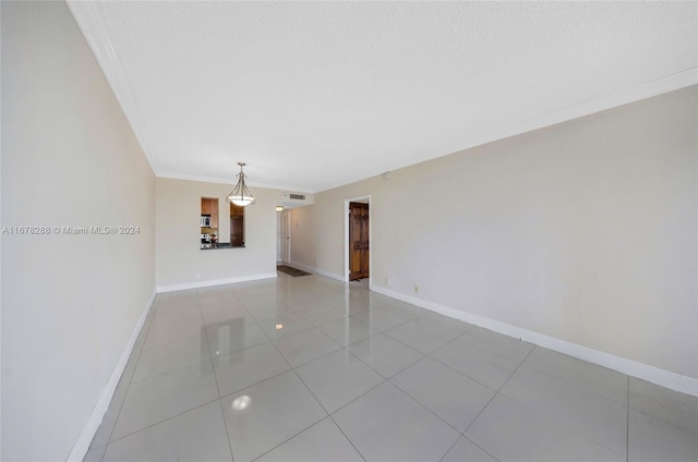 spare room featuring ornamental molding, a textured ceiling, and light tile patterned floors