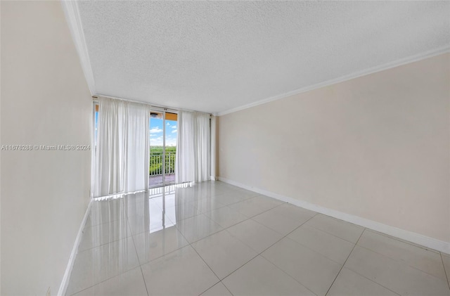 empty room with light tile patterned flooring, a textured ceiling, and ornamental molding