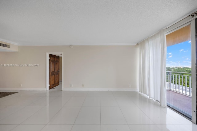 spare room with ornamental molding, a textured ceiling, and light tile patterned flooring