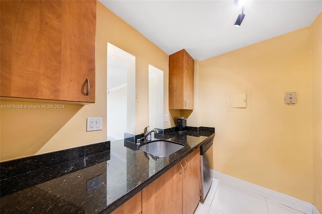 kitchen featuring sink, light tile patterned flooring, dishwasher, and dark stone countertops