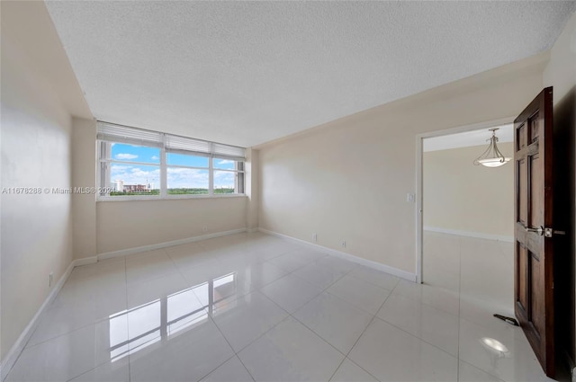 empty room featuring a textured ceiling and light tile patterned floors