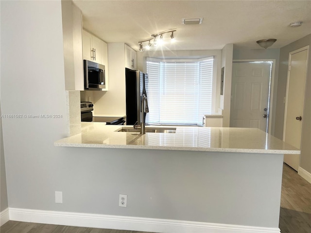 kitchen with kitchen peninsula, white cabinets, stainless steel appliances, and hardwood / wood-style floors