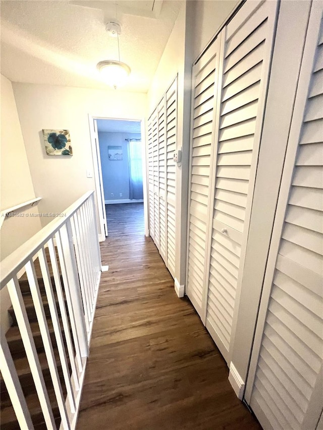 hall with a textured ceiling and dark hardwood / wood-style floors