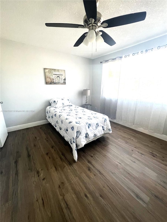 bedroom with a textured ceiling, dark hardwood / wood-style floors, and ceiling fan