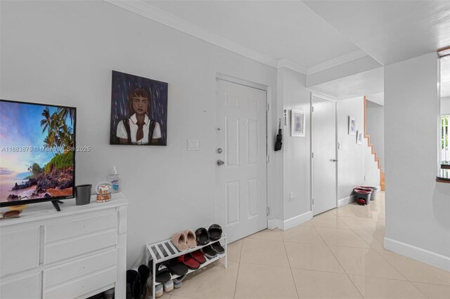 entryway with stairway, ornamental molding, light tile patterned floors, and baseboards