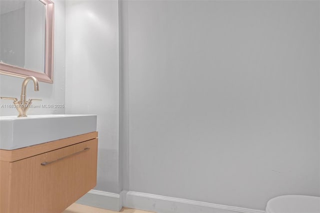 bathroom featuring baseboards, vanity, and toilet
