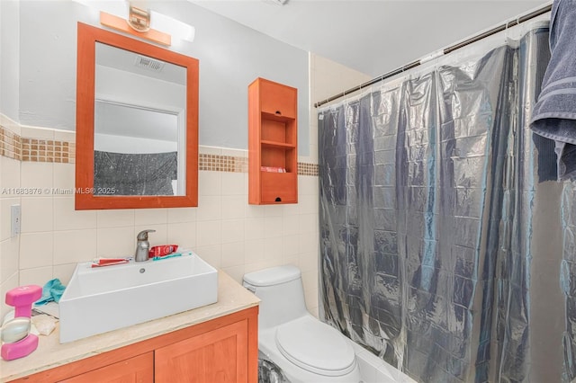 bathroom with tile walls, toilet, vanity, and a shower with shower curtain