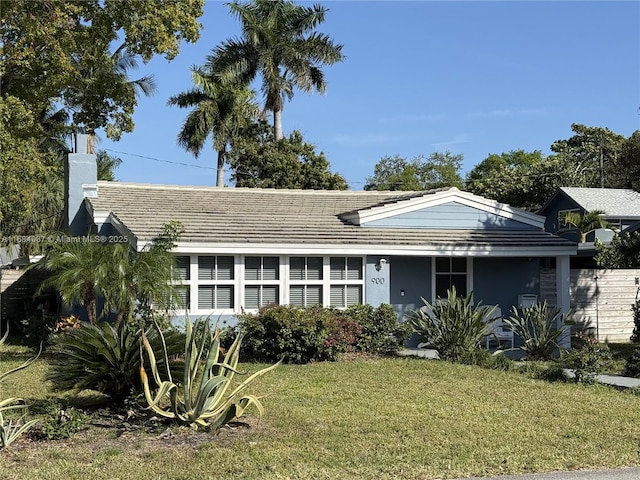 view of front facade featuring a tiled roof, a front lawn, a chimney, and stucco siding