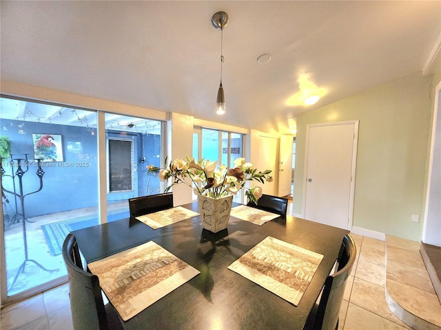 dining space with light tile patterned floors and vaulted ceiling