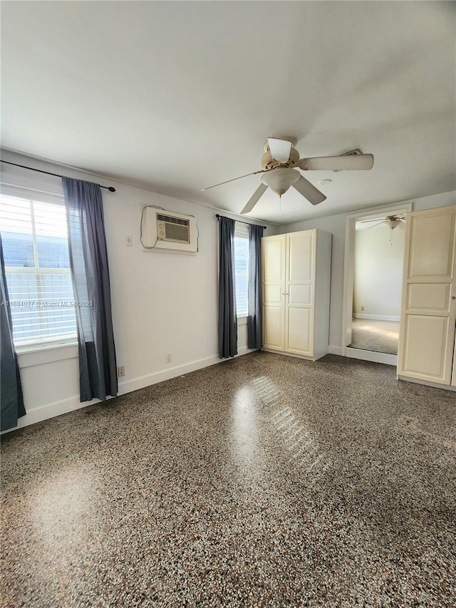 unfurnished bedroom with a wall unit AC and ceiling fan