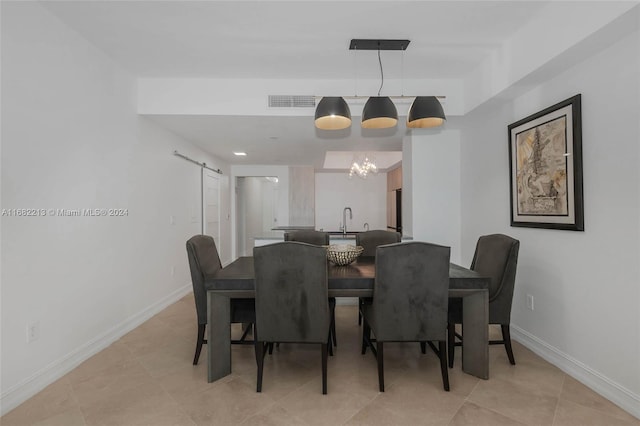 dining space with light tile patterned flooring, sink, and a barn door