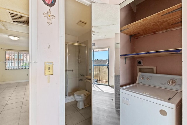 bathroom featuring toilet, an enclosed shower, washer / clothes dryer, and tile patterned flooring