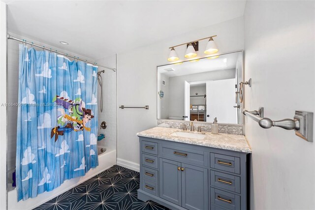 bathroom with baseboards, shower / bath combination with curtain, and vanity
