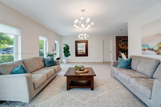 living room featuring an inviting chandelier, light wood-type flooring, and a wealth of natural light