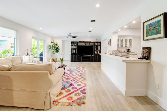 living room featuring ceiling fan and light hardwood / wood-style flooring