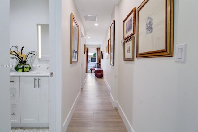 hallway featuring sink and light hardwood / wood-style floors