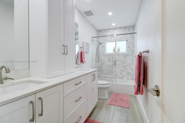 full bathroom featuring toilet, vanity, and shower / bath combination with glass door