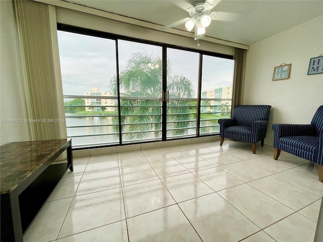 living area featuring ceiling fan, a water view, and light tile patterned floors