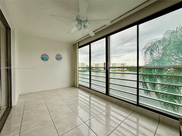 unfurnished sunroom with a water view and ceiling fan