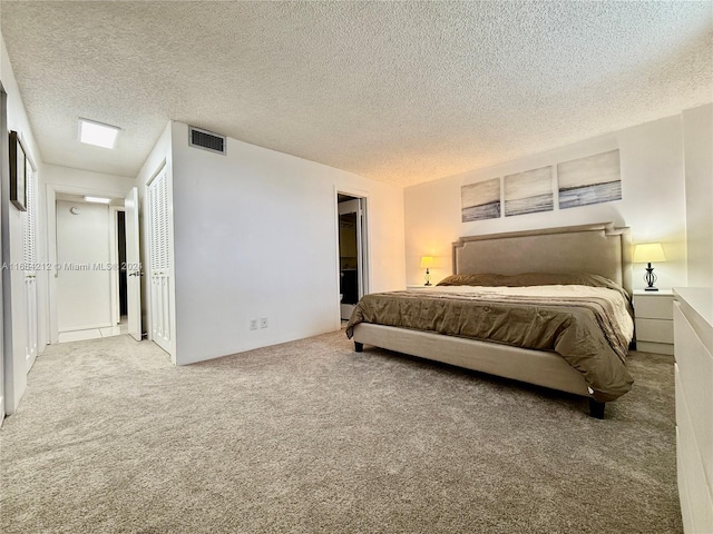 bedroom with a textured ceiling and light colored carpet