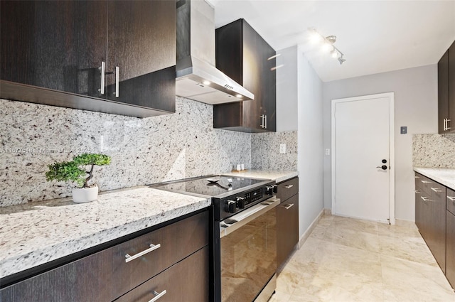 kitchen with dark brown cabinetry, light stone counters, tasteful backsplash, stainless steel electric stove, and exhaust hood