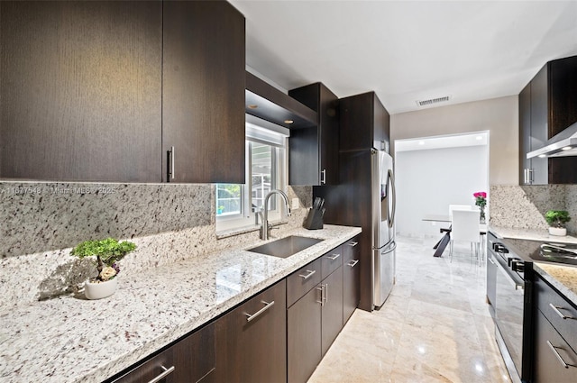 kitchen with light stone counters, black / electric stove, decorative backsplash, and sink