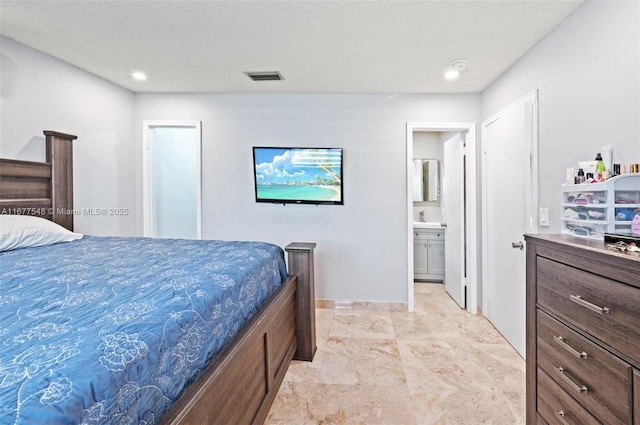 bedroom with ensuite bathroom, sink, and a textured ceiling