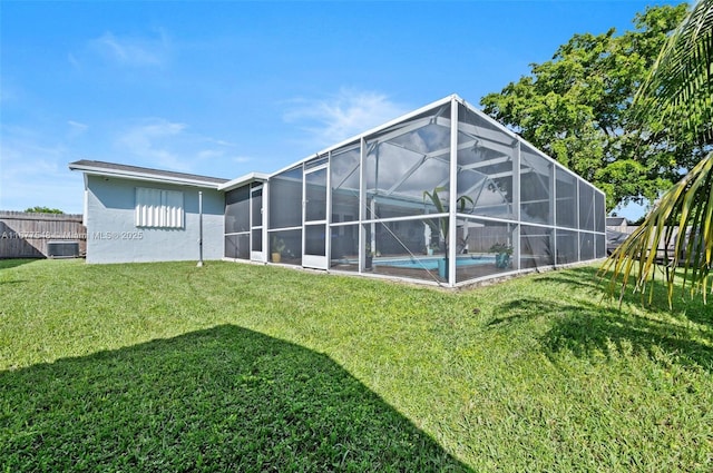 back of house with central AC, a yard, and glass enclosure