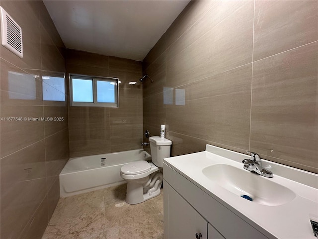 full bathroom featuring tiled shower / bath, vanity, toilet, and tile walls