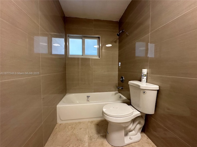 bathroom with tile walls, tiled shower / bath combo, and toilet