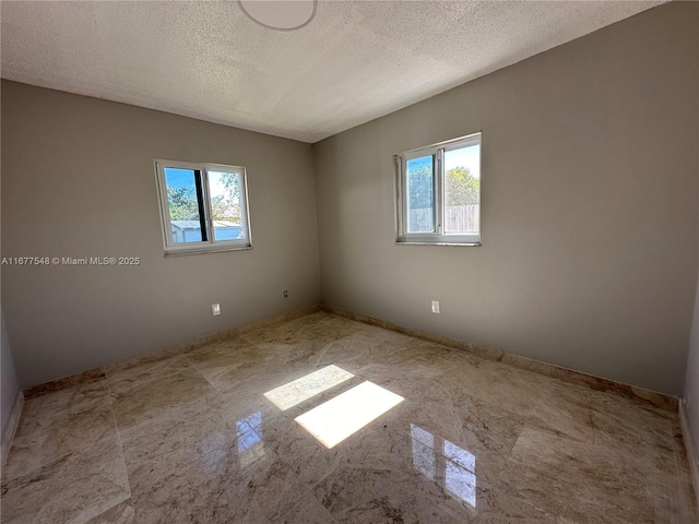 unfurnished room featuring plenty of natural light and a textured ceiling