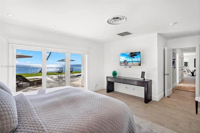 bedroom with a water view, light hardwood / wood-style floors, and access to outside