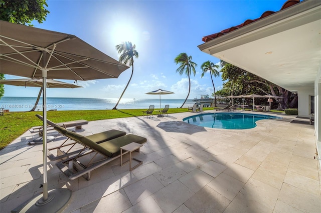 view of pool featuring a patio, a yard, and a water view