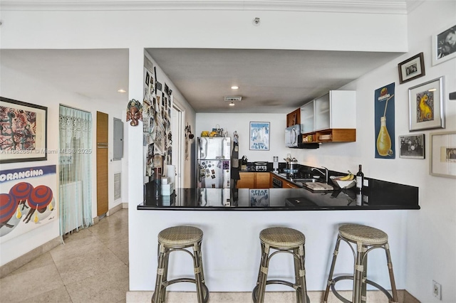 kitchen with white cabinetry, kitchen peninsula, stainless steel refrigerator, and a breakfast bar area