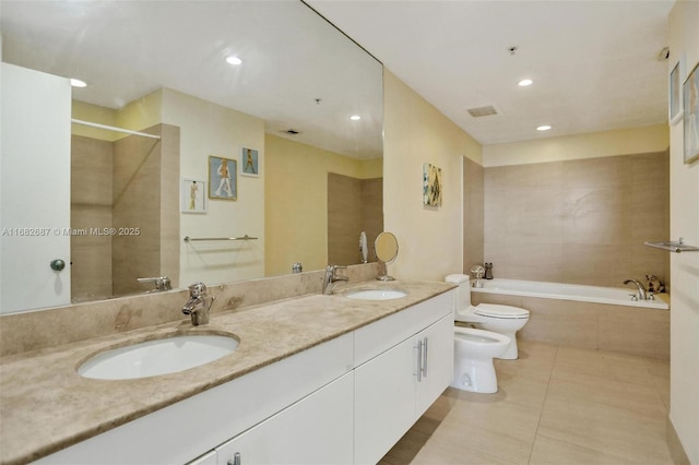 bathroom featuring tile patterned floors, toilet, vanity, a relaxing tiled tub, and a bidet