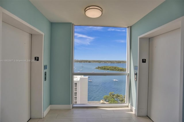 doorway to outside featuring a water view, expansive windows, and elevator