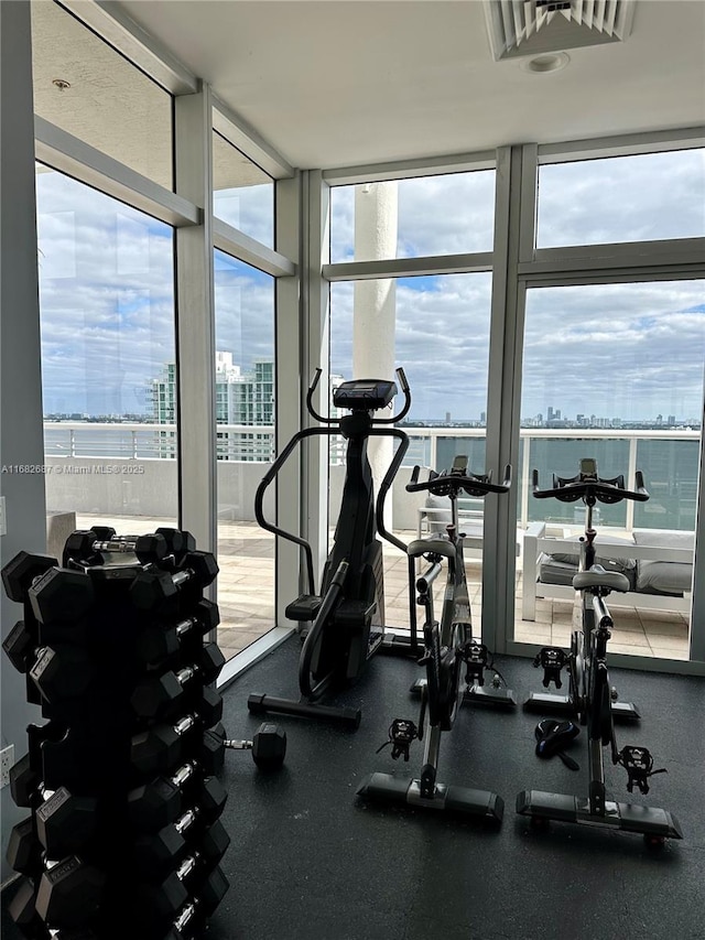 exercise room featuring a wall of windows and a water view