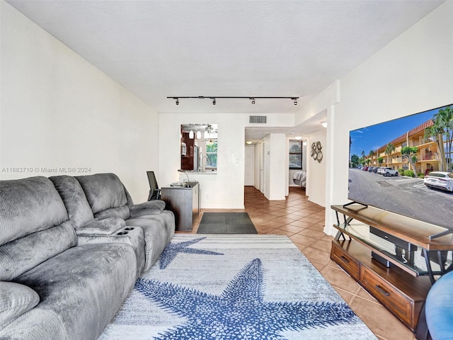 living room featuring a textured ceiling, rail lighting, and light tile patterned floors