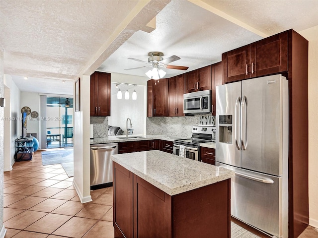 kitchen featuring sink, a textured ceiling, stainless steel appliances, and a kitchen island